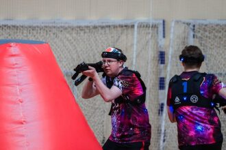 Игрок LASERWAR с автоматом у красного укрытия в движении.